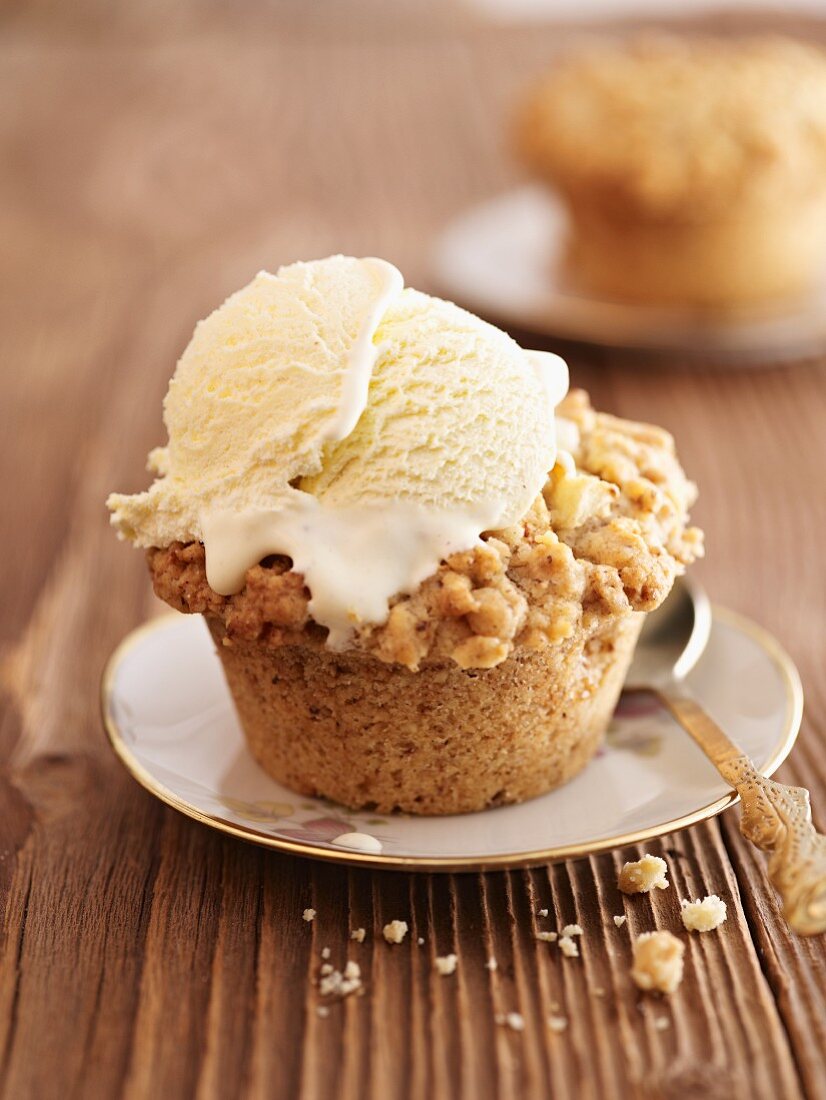 An apple cupcake with crumbles and vanilla ice cream