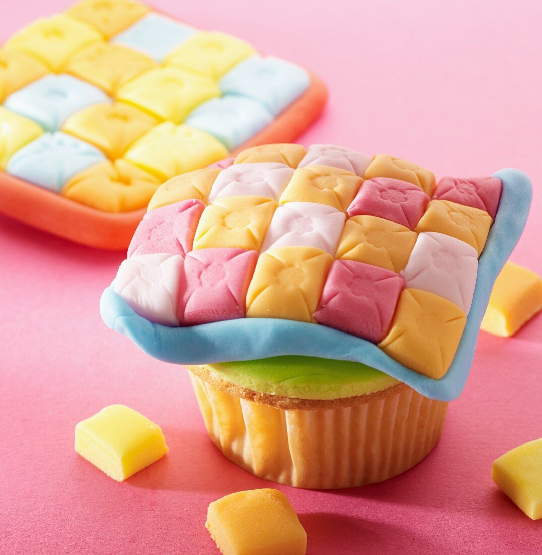 A cupcake decorated with a baby blanket