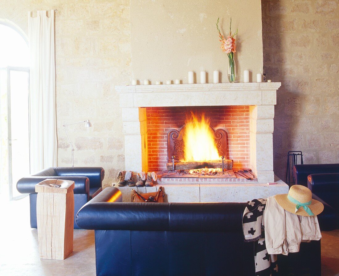 Sitzecke mit Ledersessel & Ledercouch vor offenem Kamin im Château Maignaut (Pyrenäen, Frankreich)