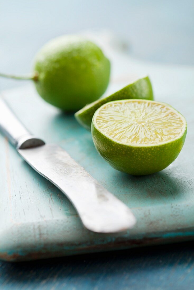 Halbierte Limette und Messer auf blauem Holzbrett