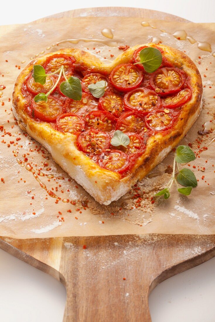 A heart-shaped pizza topped with tomatoes