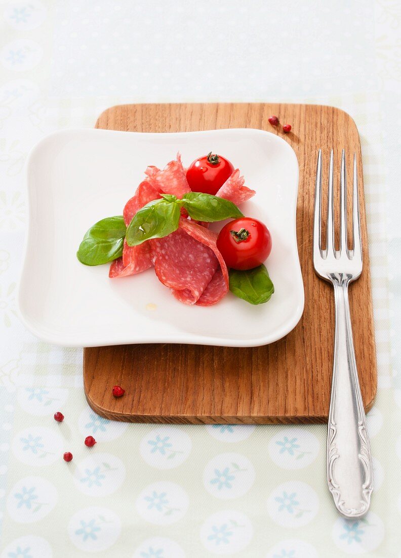 Sliced salami with basil and tomatoes