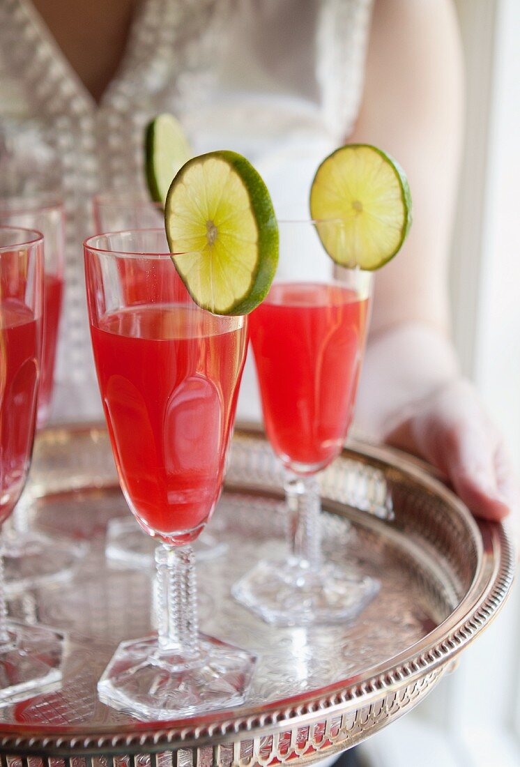 A woman holding a tray of cocktails