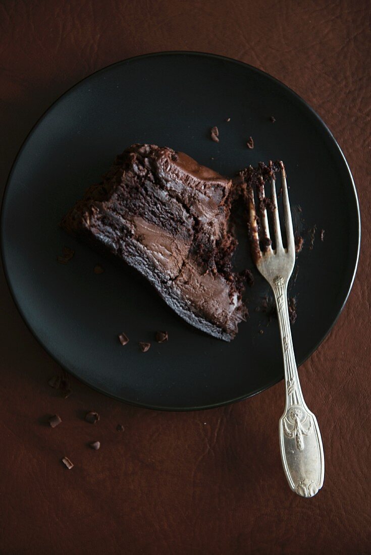 A slice of chocolate truffle cake with a bite taken out of it