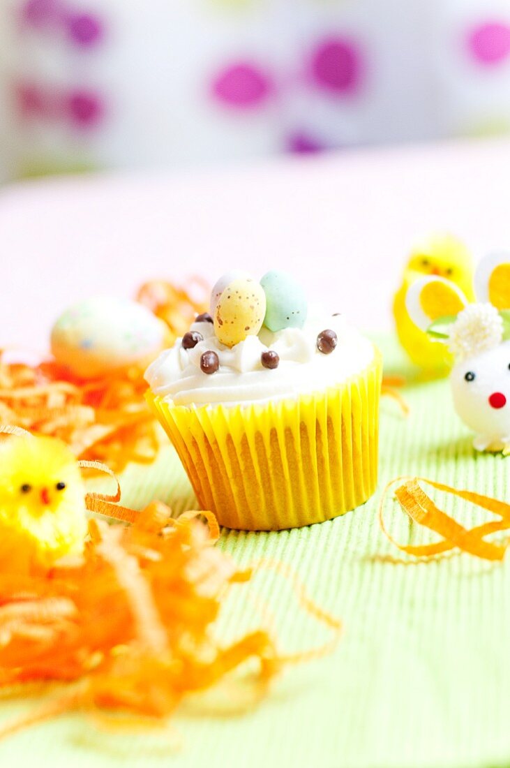 A cupcake with vanilla frosting and sugar eggs for Easter