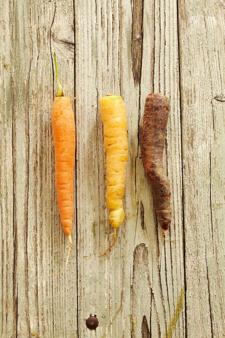 Three different carrots on a wooden surface