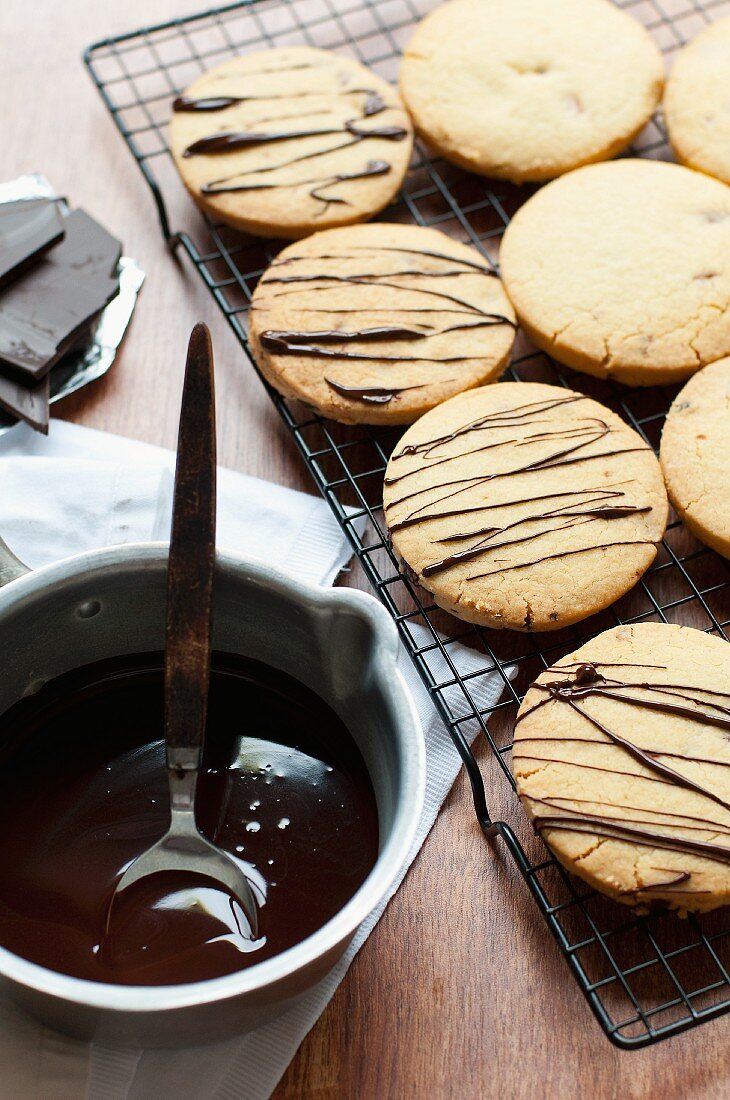 Shortbread cookies drizzled with chocolate on a wire rack