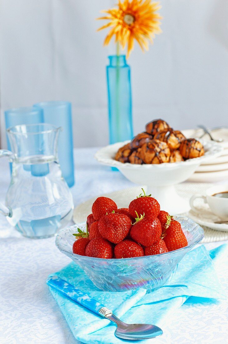 Frische Erdbeeren in Glasschale, Wasserkrug, Profiteroles