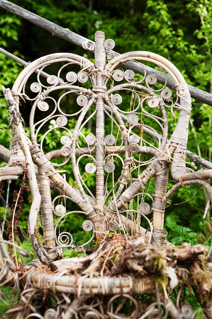 Old, partially rotted wicker chair in garden