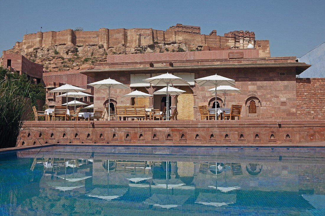 Restaurant tables and parasols next to swimming pool of Raas Haveli Hotel, Jodhpur, India