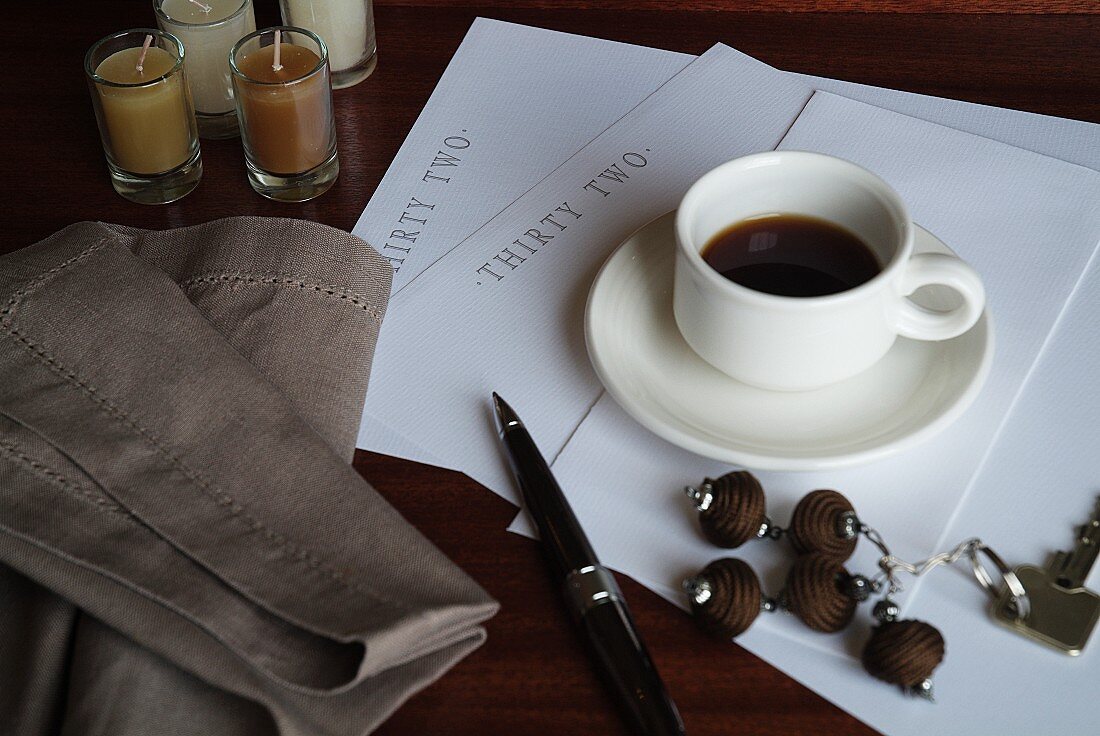 Writing paper and ball-point pen next to cup of coffee on table