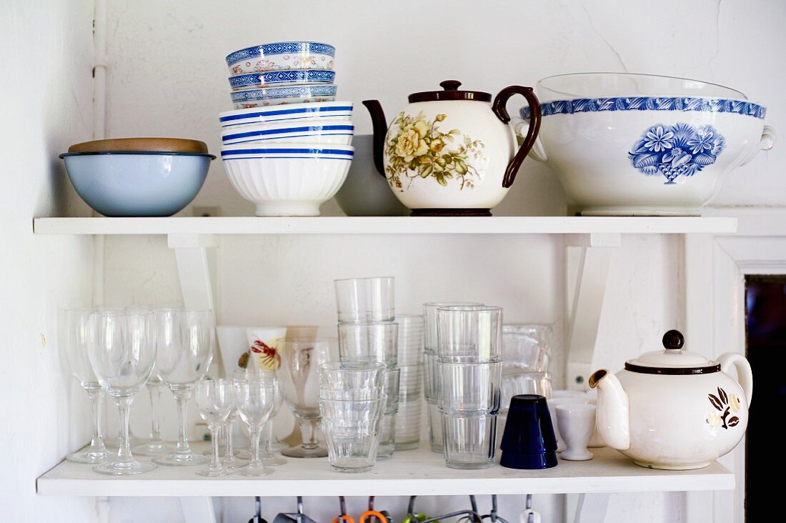 Geschirr und Gläser auf Konsolenregal in schlichter Zimmerecke