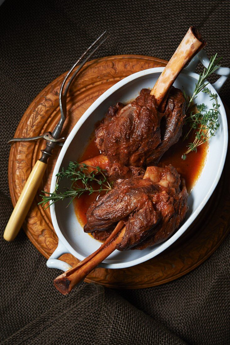 Braised Lamb Shank on an Oval Dish with Fresh Herbs