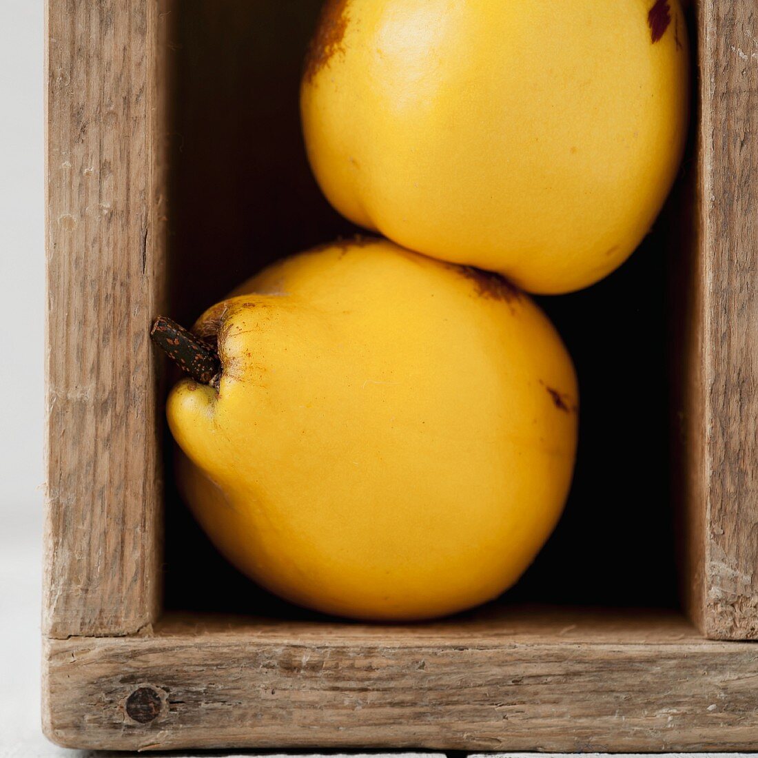 Two quinces in a wooden crate