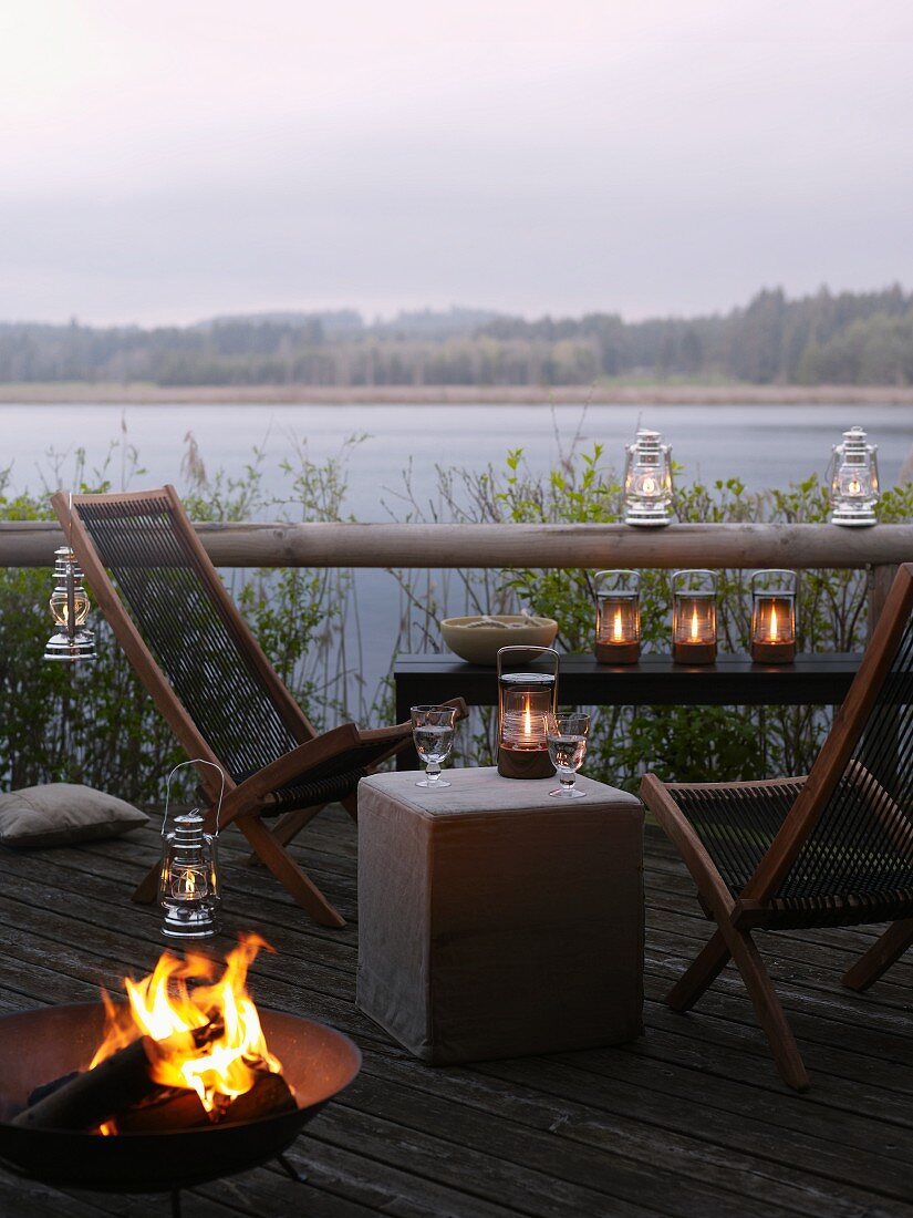 Deckchairs, fire bowl and lanterns on lakeside terrace