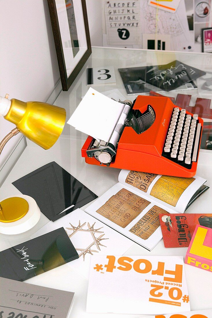 Orange typewriter and gold table lamp on desk