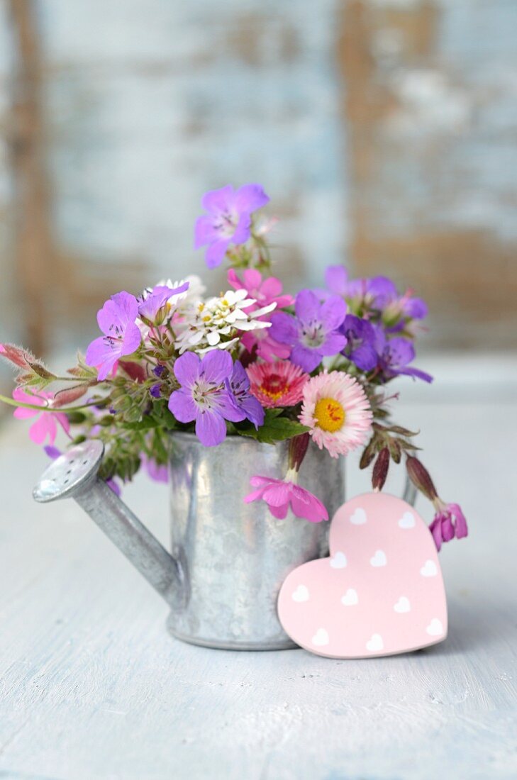 Garden posy in metal watering can with pink decorative heart