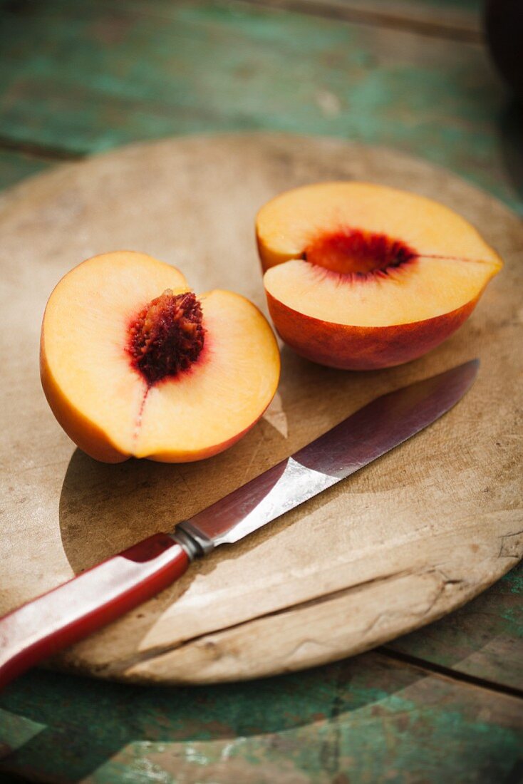 Halved Peach on a Cutting Board with a Knife