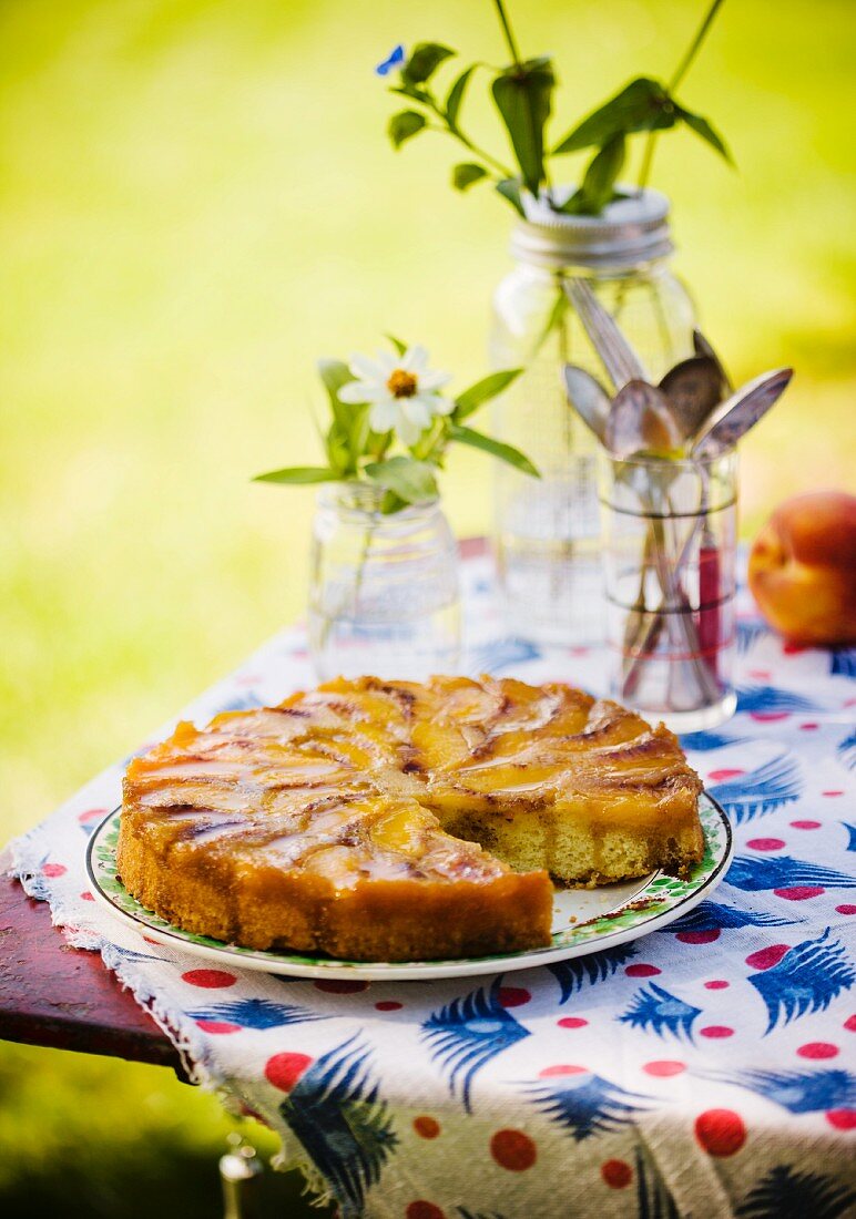 Peach Upside Down Cake with a Slice Removed; On a Table Outside
