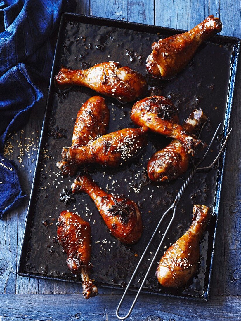 Marinated chicken legs with sesame seeds, on a baking tray