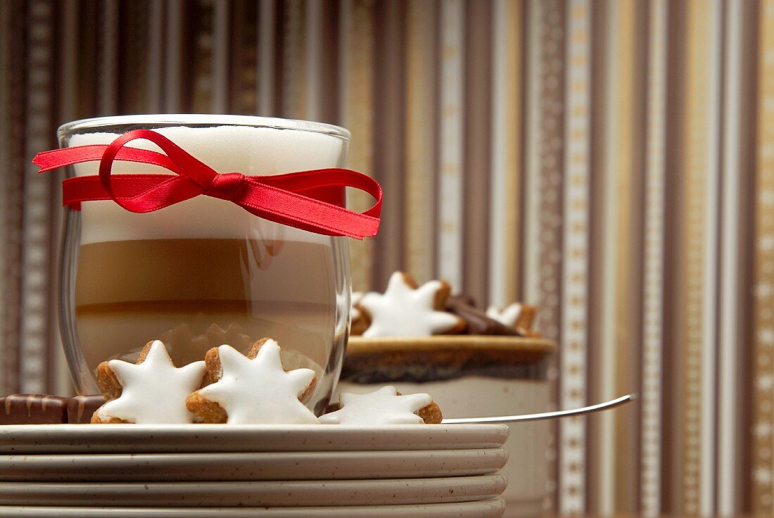 Cinnamon stars and chocolate covered marzipan with a latte macchiato with a red bow