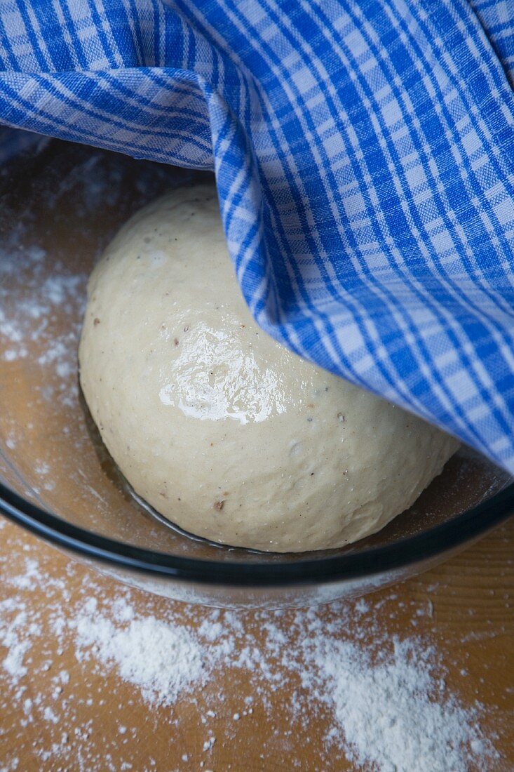 Towel Pulled Aside to Show Bread Dough Proofing in a Bowl