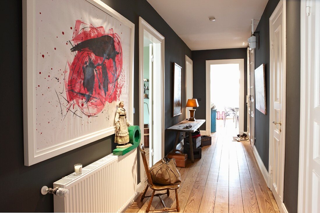 View along hall in renovated period building with wooden floor and modern artworks on walls