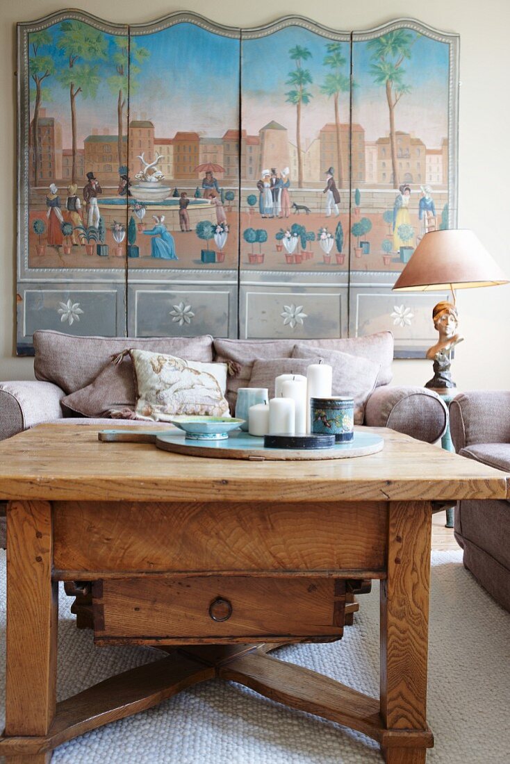 Rustic coffee table and upholstered armchairs in front of multi-panelled picture