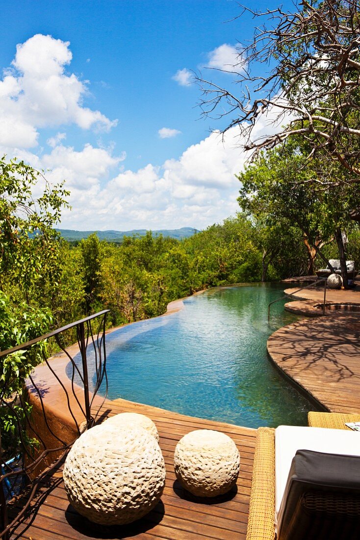 Holzterrasse mit geschwungenem Pool und mit herrlichem Landschaftsblick