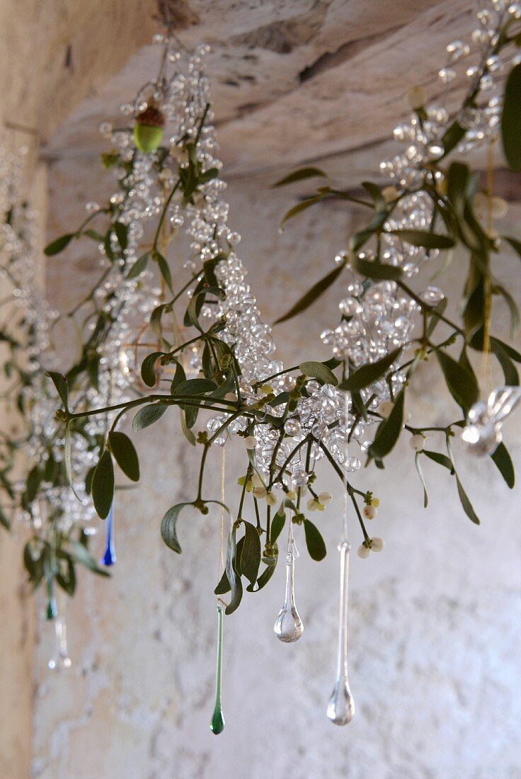 Christmas garland of glass beads, hand-blown glass droplets and mistletoe hanging in window niche in old, sandstone walls