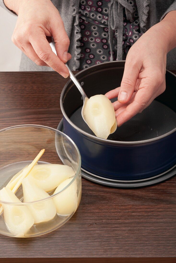 Stewed pears being placed in a cake tin