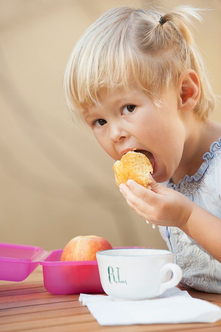 A little girl eating cake dunked in milk