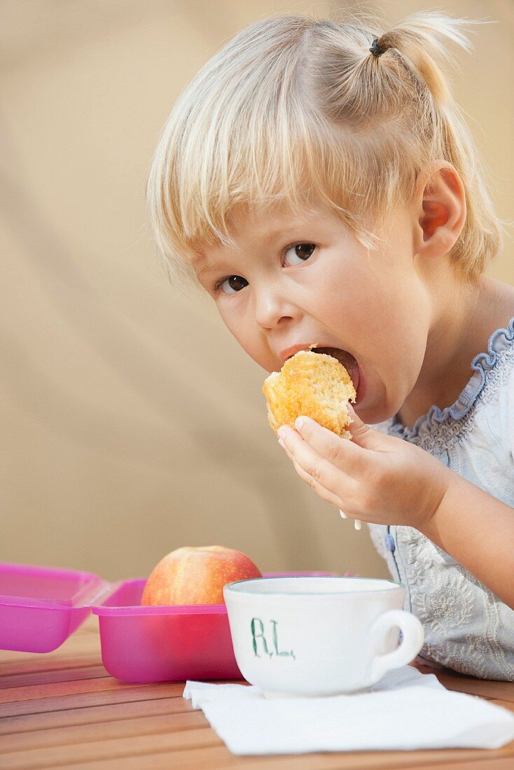 Kleines Mädchen isst in Milch getauchten Kuchen