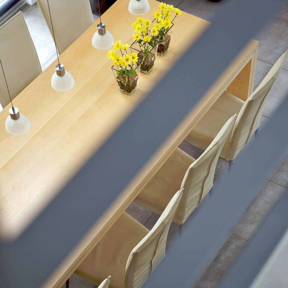 Top view of dining area with yellow bouquets in glass vases and modern pendant lamps with glass lampshades