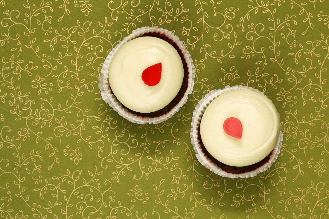 Zwei Red Velvet Cupcakes mit je einem Zucker-Blütenblatt