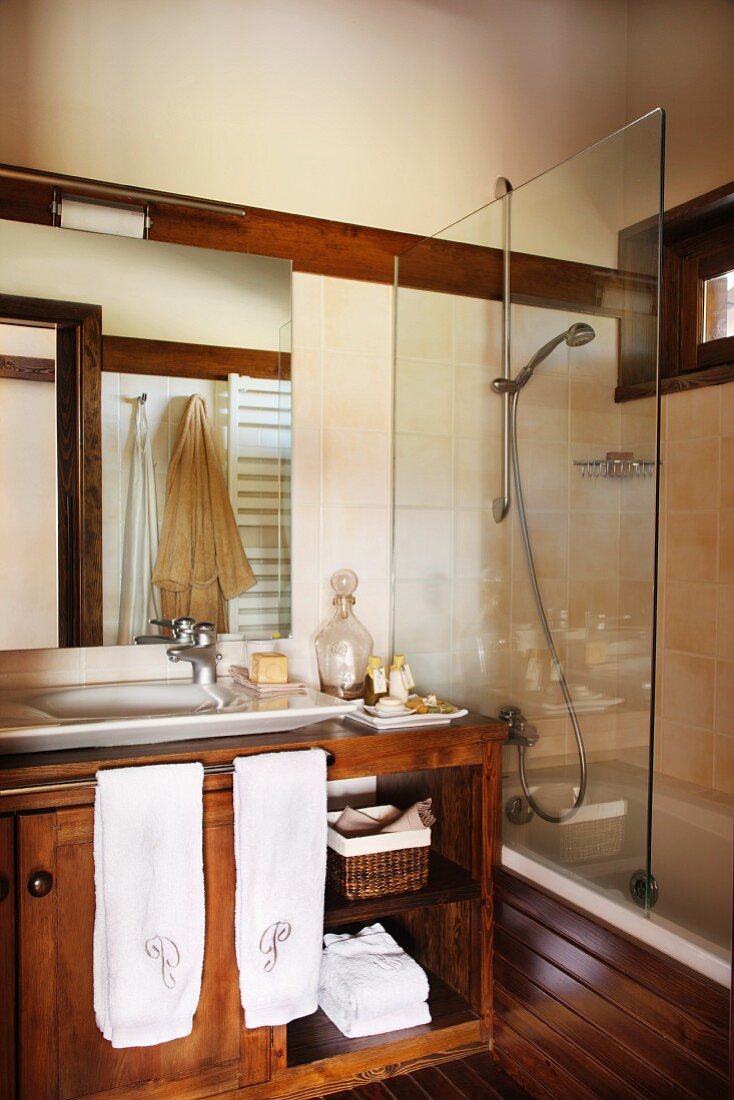 Badezimmer mit Waschtisch-Unterschrank, daneben Badewanne mit Glasabtrennung