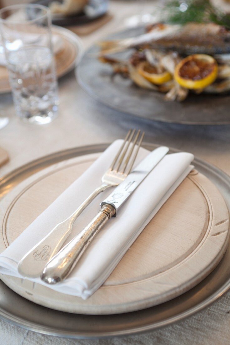 Stylish place setting with a wooden plate, napkin and silver cutlery