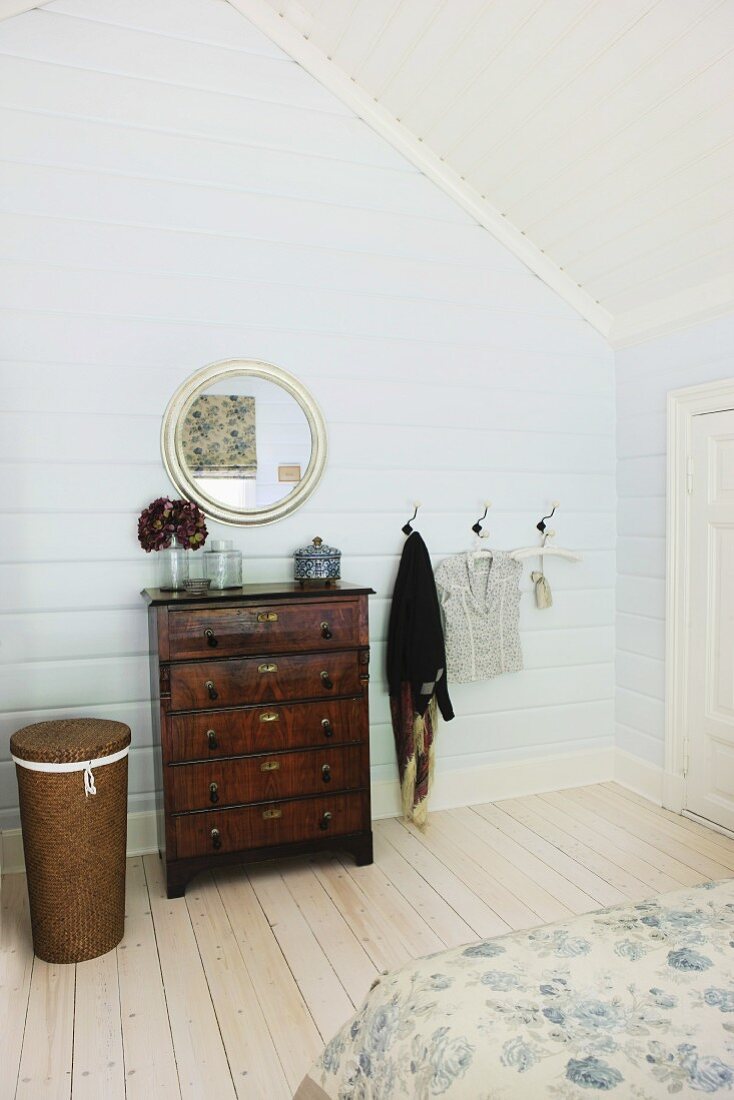Antike Schubladenkommode und runder Spiegel im Schlafzimmer im Dachgeschoss mit Holzverkleidung