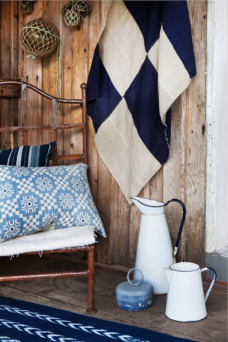 Fabrics in various patterns of blue and white and old enamel jugs on wooden terrace