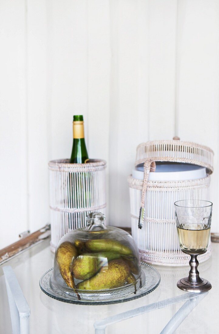 Bottle in hand-crafted container laced with cord and pears under glass bell jar