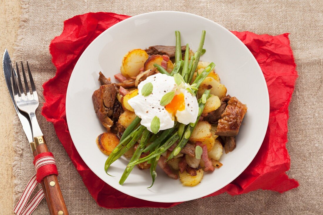 Gröstl (typical Tirolean dish using leftovers) with potatoes, pork, green beans and a poached egg
