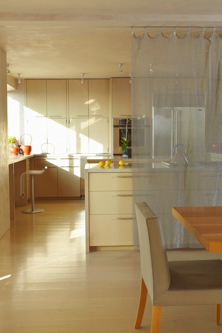 Dining area in front of an open kitchen with center block and transparent curtain as a screen