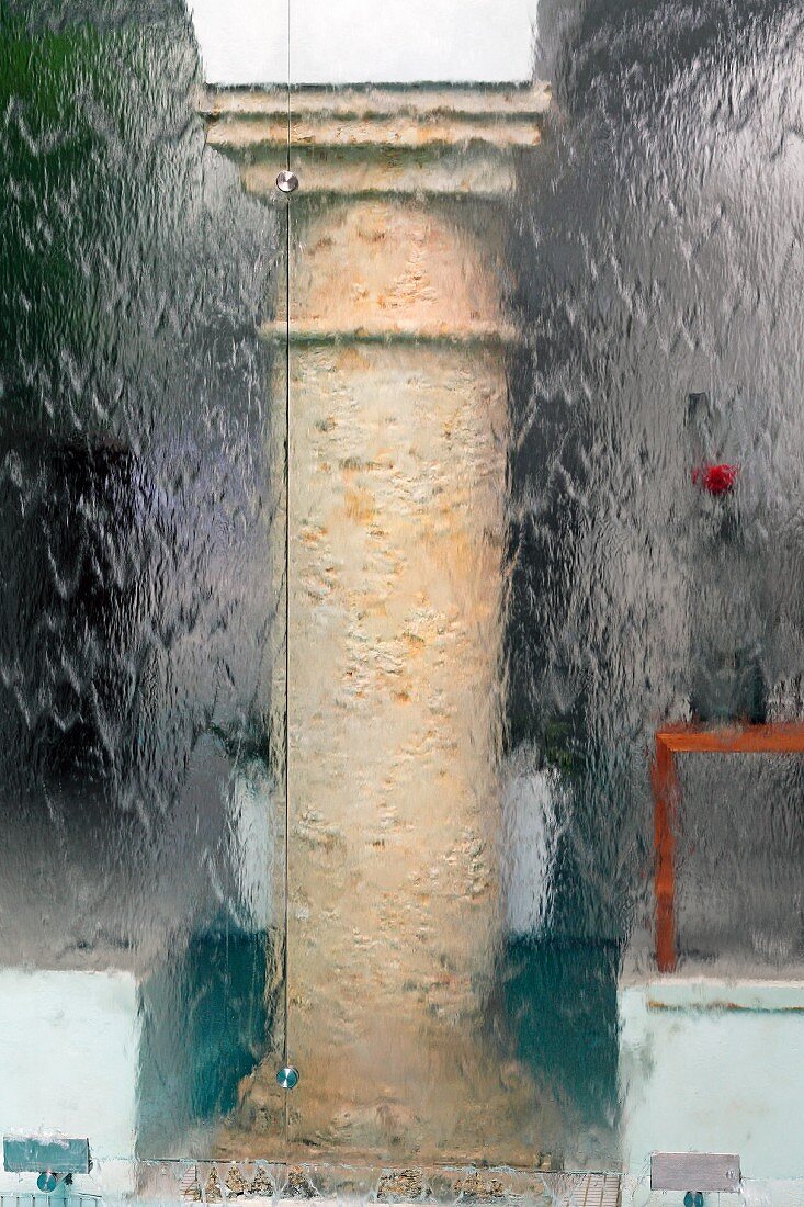 Blurred view of stone column in courtyard through glass wall