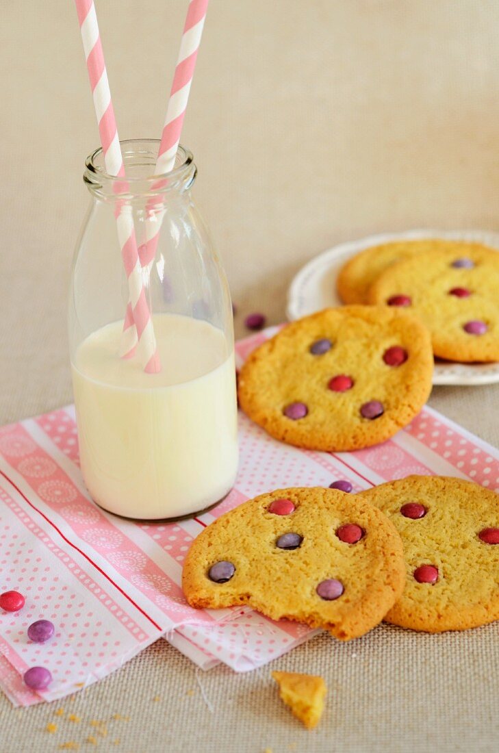 Sable biscuits with coloured chocolate beans, and a milk bottle with drinking straws
