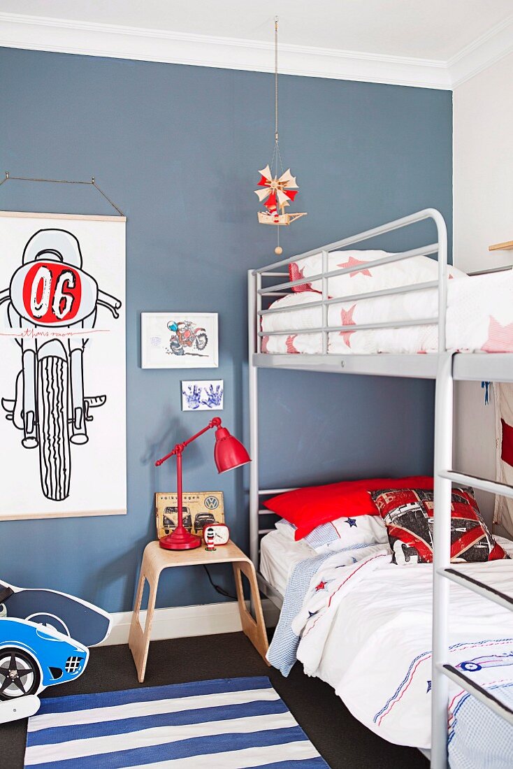 Stockbett mit Metallgestell in blau getöntem Jugendzimmer und Zeichnungen mit Motorradmotiven