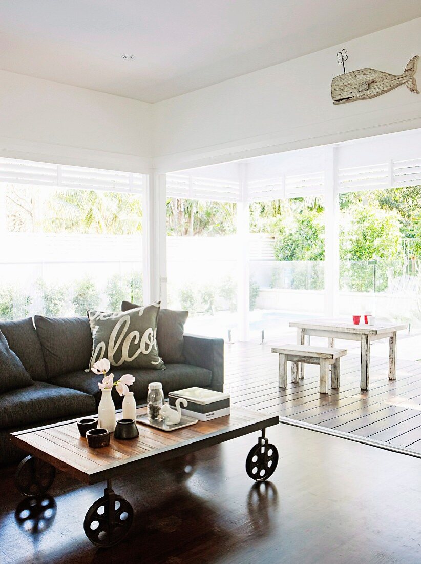 Living area with sofa, coffee table on castors & open sliding doors leading to veranda