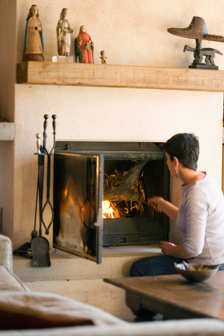 Lady stoking a fire - painted statues on a rustic, square timber mantelpiece