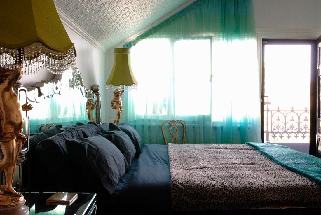 Double bed flanked by postmodern bedside lamps in bedroom with embossed cladding on sloping ceiling