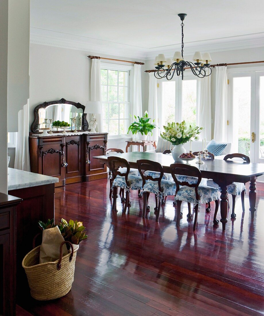 Reddish, shimmering precious wood takes command of this open kitchen-living room with traditional, antique style furniture