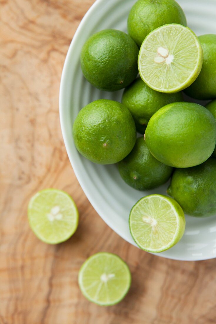 Fresh limes, whole and halved, in a dish